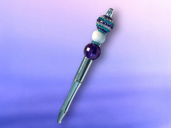 A decorative metallic pen with a top adorned with purple, white, and teal crystal beads.