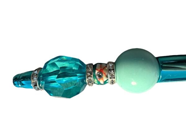 A decorative pen body featuring a large faceted teal bead, rhinestone spacer rings, a floral bead