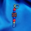 A keychain with alternating red and blue beads, a blue tassel, and a charm reading "Faith over Fear."