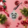 A white ornament featuring a black Nativity scene with angels, surrounded by colorful Christmas decor.
