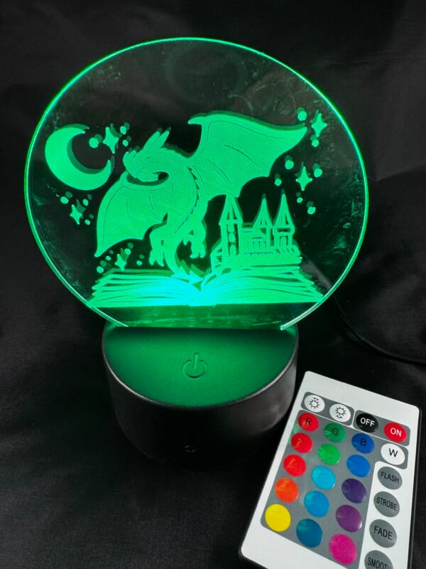 Illuminated green LED lamp displaying a dragon, castle, moon, and stars design, next to a remote control.
