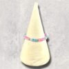 A colorful beaded bracelet with pink, blue, and gold beads rests on a cream display cone.