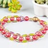 A vibrant beaded bracelet featuring coral spherical beads alternating with colorful rectangular beads.