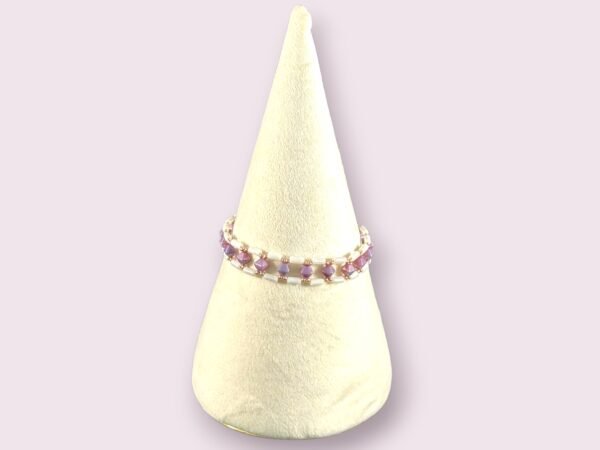 A two-strand beaded bracelet featuring purple faceted beads and white tube beads on a stand.