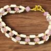 A delicate two-row beaded bracelet with cream cylindrical and lavender faceted beads.