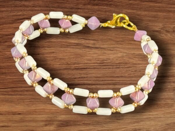 A delicate two-row beaded bracelet with cream cylindrical and lavender faceted beads.