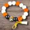Round silicone beaded keychain with white, orange, black, leopard print beads, gold clasp, and white tassel.