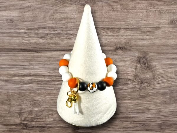 Orange, white, and black silicone bead wristlet keychain with a patterned bead, gold keyring, and tassel.