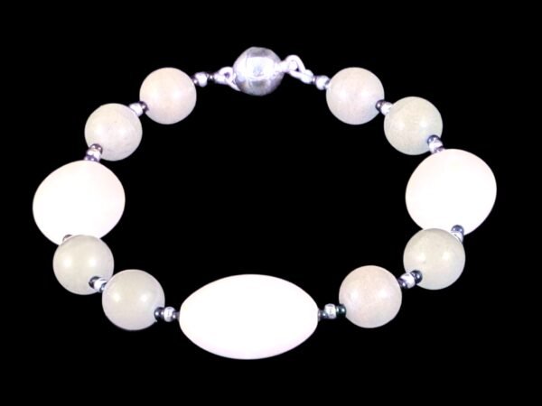 Smoke gray round bead bracelet with 3 large white ovals, silver and black accent spacers, and a silver magnetic clasp, shown against a black background.