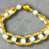 Beaded bracelet featuring white square and golden tube beads, with green spacers and a magnetic clasp.