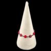 A red beaded bracelet with carved leaf-shaped beads on a white cone display stand.